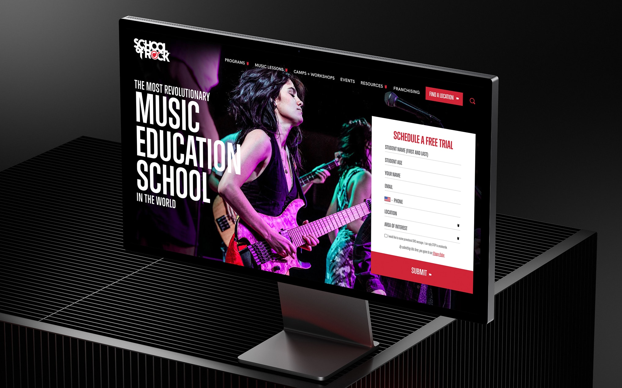 Large monitor on a dark backdrop displays a music-education website featuring a guitarist on stage and a red Schedule a Free Trial form.