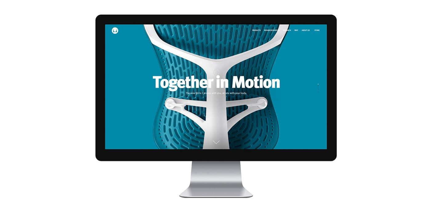 Desktop monitor displaying a teal background ad featuring a white ergonomic chair frame and the words "Together in Motion".