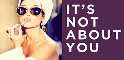Person wearing sunglasses and a white towel wrap applies lipstick; on the right, bold white text 'IT'S NOT ABOUT YOU' on purple.