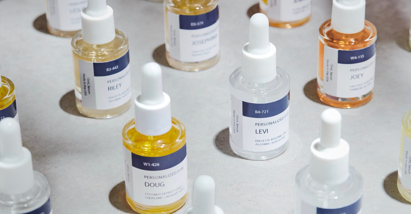 Assorted dropper bottles with colored liquids on a pale surface; labels read personalized names such as Doug, Levi, Riley, and Joey.