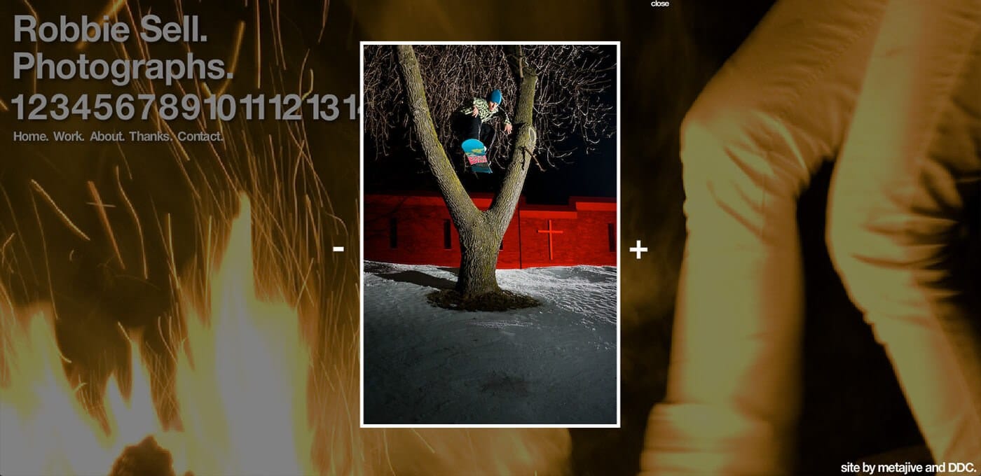 Person in blue on a swing attached to a tree, snow-covered ground, nighttime scene with a red wall in the background.