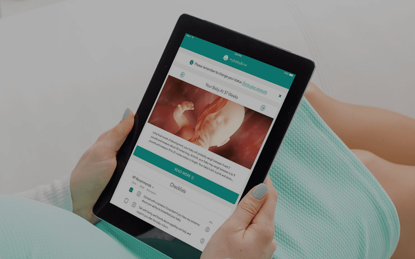 Person wearing teal clothing holds a tablet displaying a pregnancy app with a fetal image and checklists.