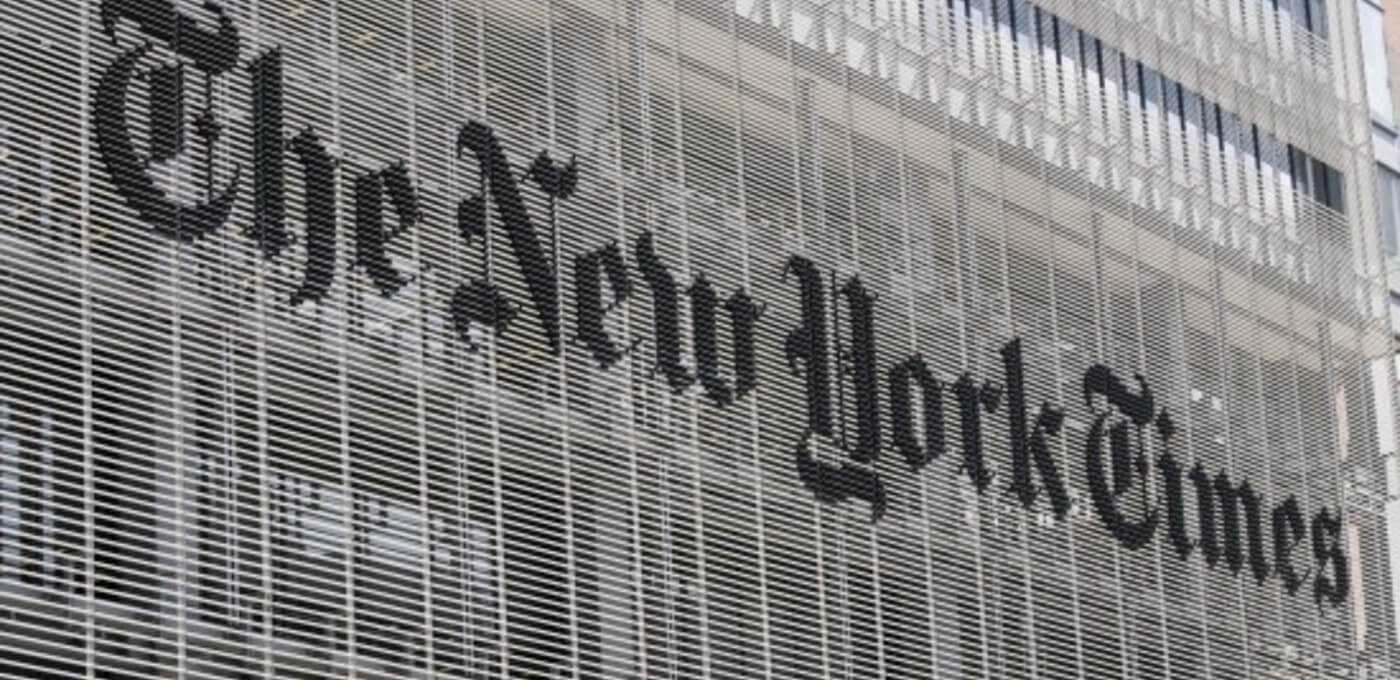 The New York Times sign in blackletter script on a glass wall with a striped metal grid facade.