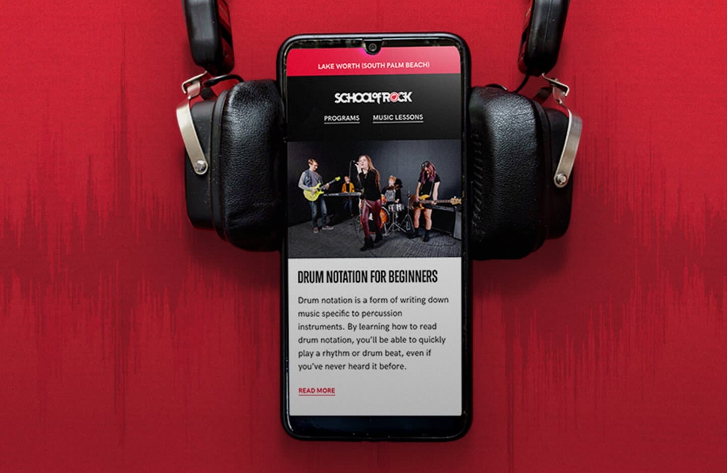 Smartphone on a red background, flanked by headphones, displaying a music lesson app page titled Drum Notation for Beginners with a band photo.